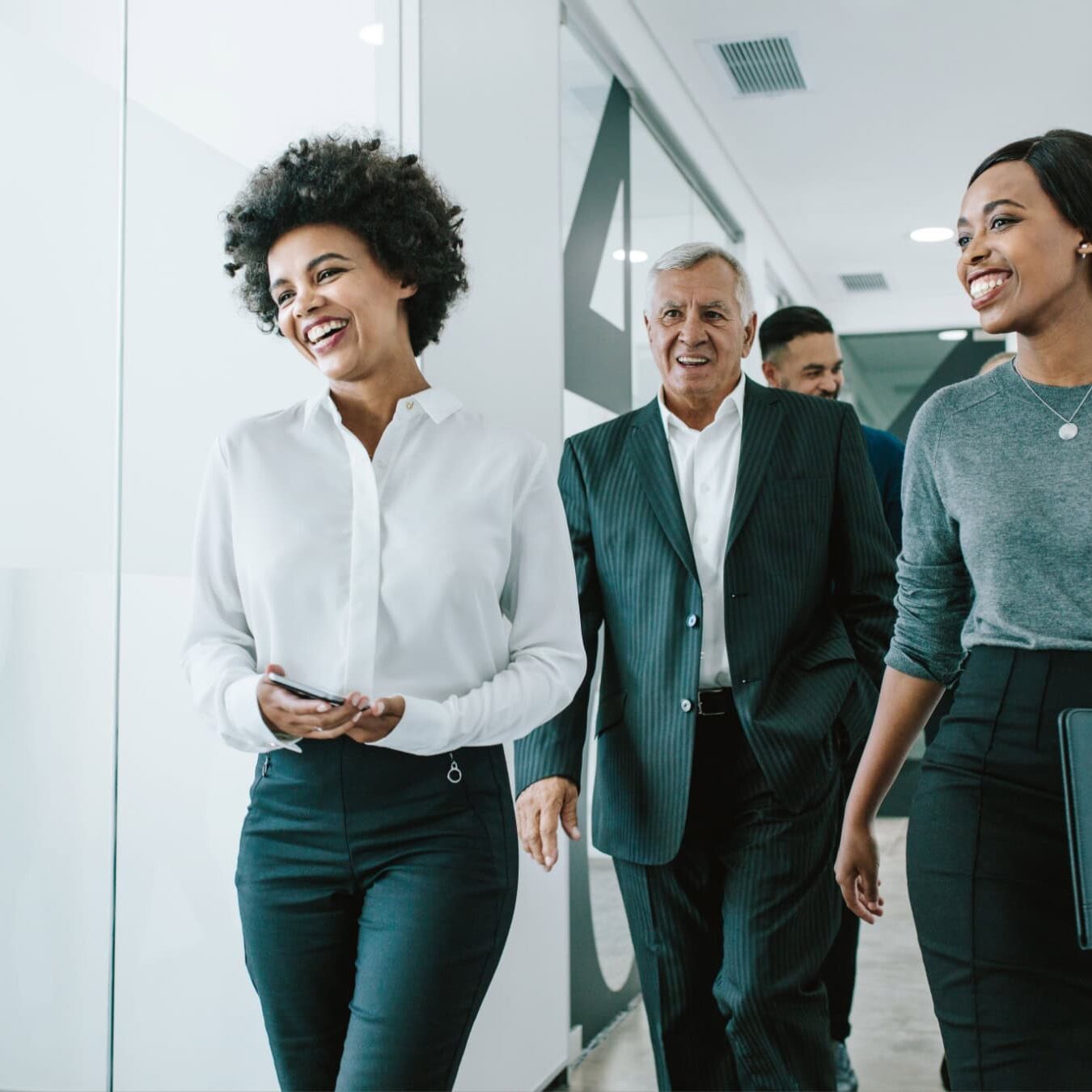 A group of coaching professionals walk and talk through an office hallway