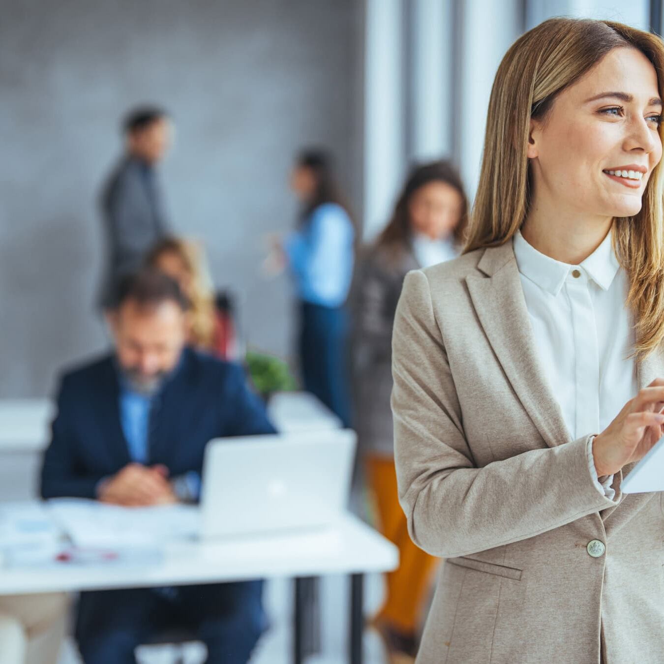 A woman standards a the front of a classroom on her tablet