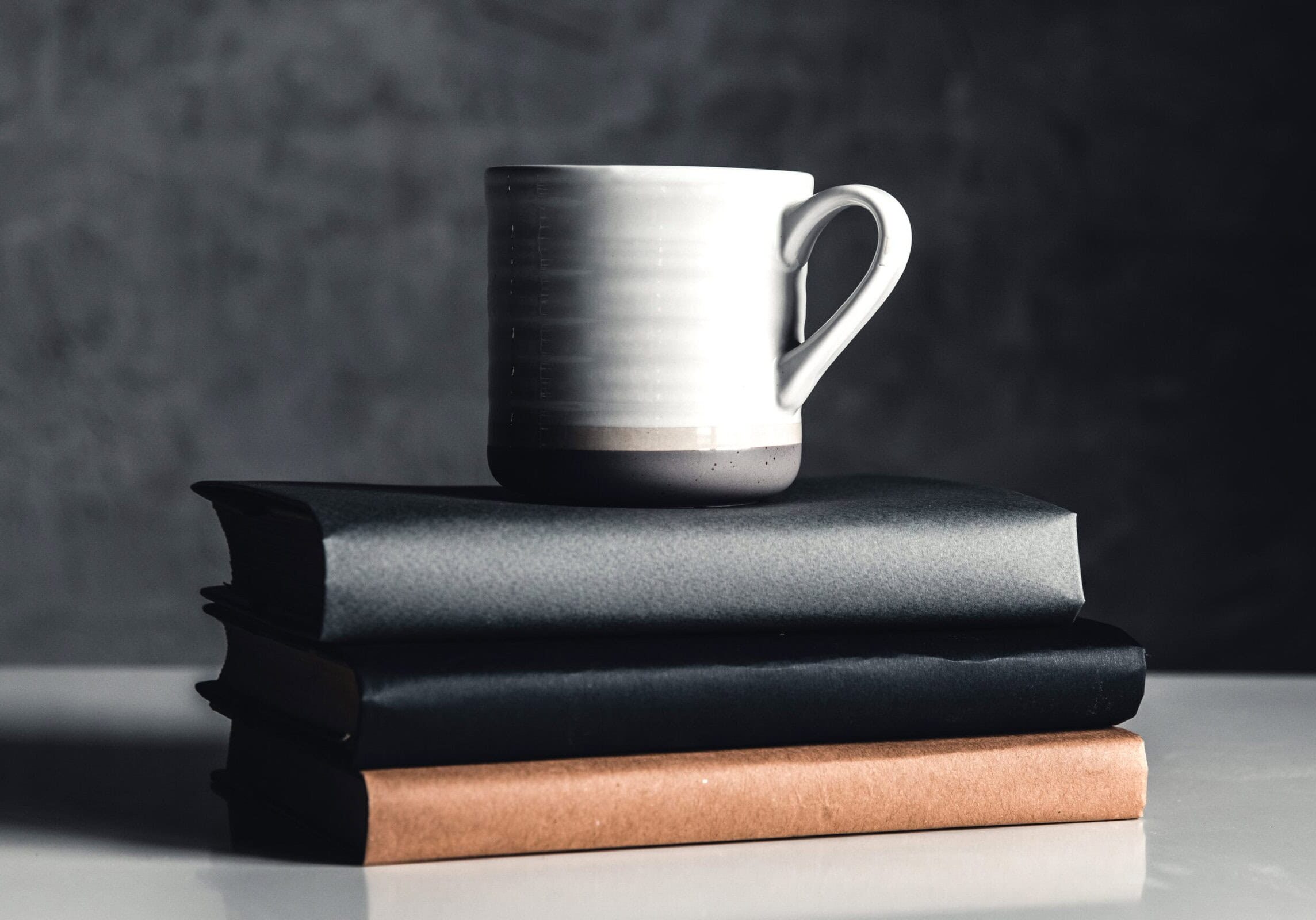 Books stacked with a ceramic coffee mug on top, symbolizing a reflective learning environment for coaching education