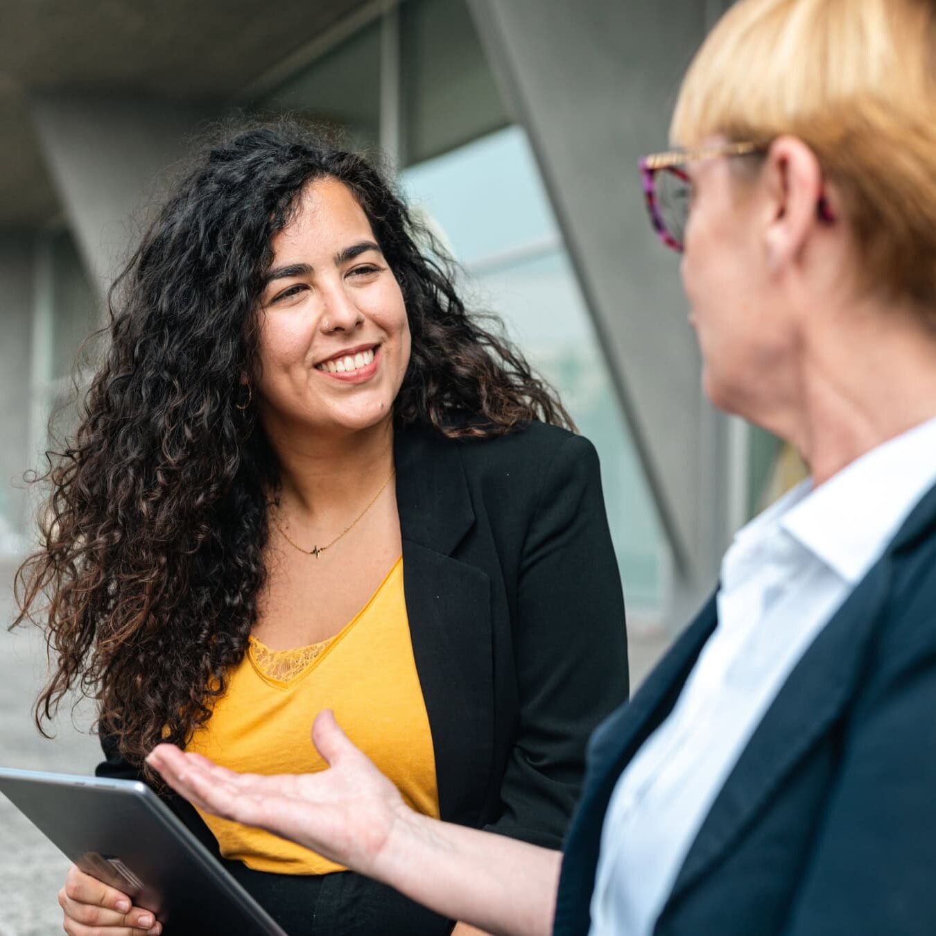 Two people compare the ICF Coaching credentials outside with an Ipad