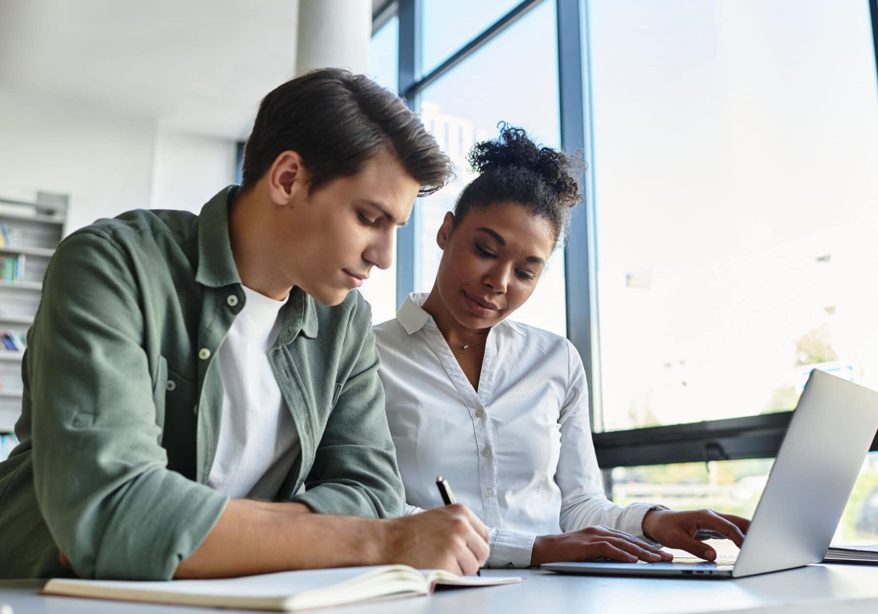 A woman is showing a man on a laptop how to file an ethical complaint