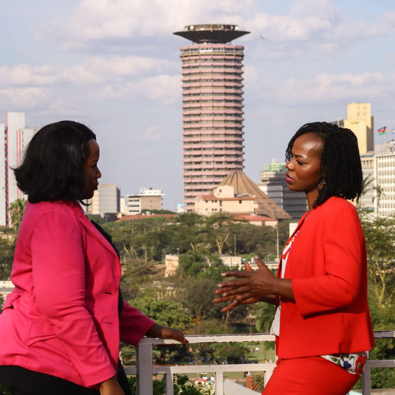 Two professional women engaging in a coaching conversation on a rooftop with Nairobi's city skyline in the background, focusing on leadership development and business growth