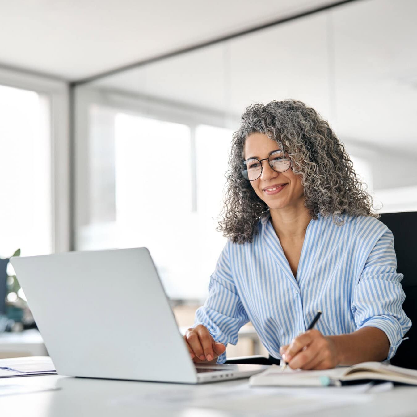 A woman looks on her laptop in an office setting