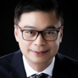Julius Ordonez ACTC MCC headshot photo, man with dark hair glasses in dark blazer and white collared shirt smiling against a black background