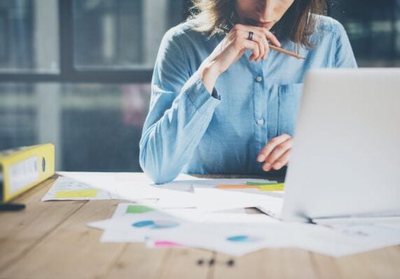 coach at a table with many scattered papers a pencil and a laptop