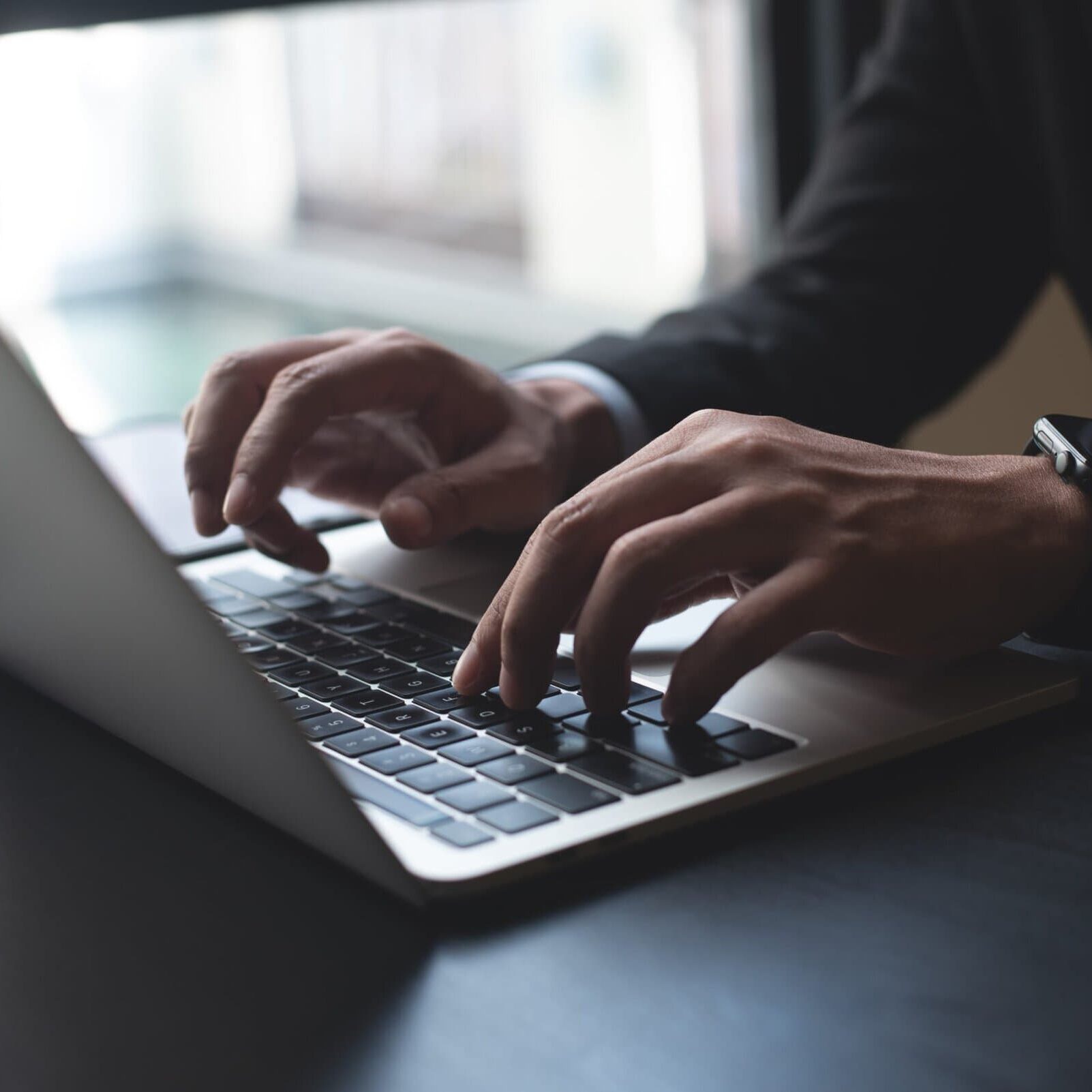business professional with hands on a macbook keyboard