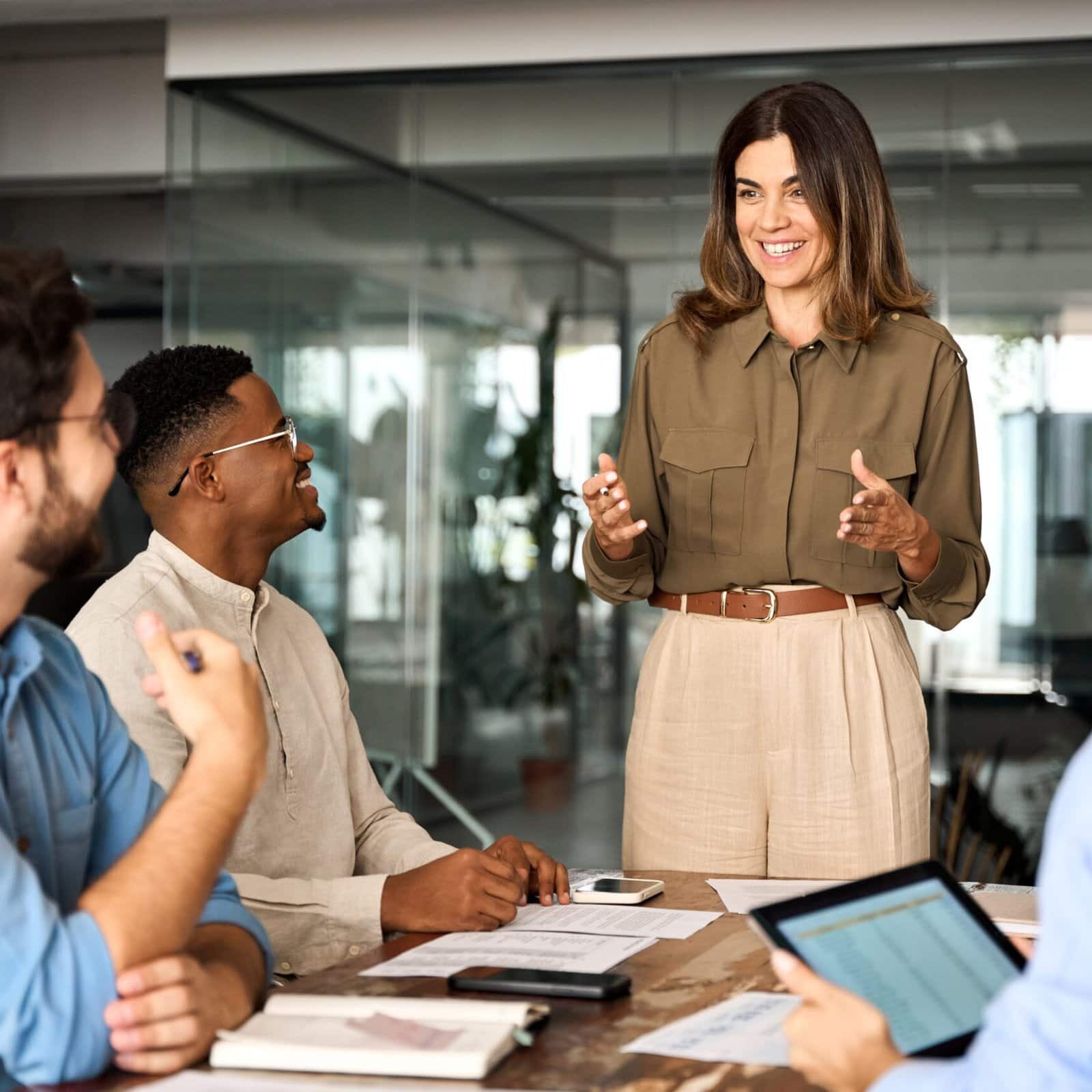 smiling coach addressing three people at a conference table