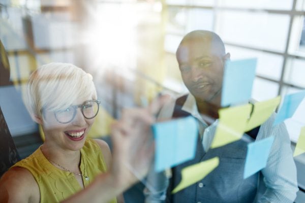 woman and man looking at sticky notes on a window